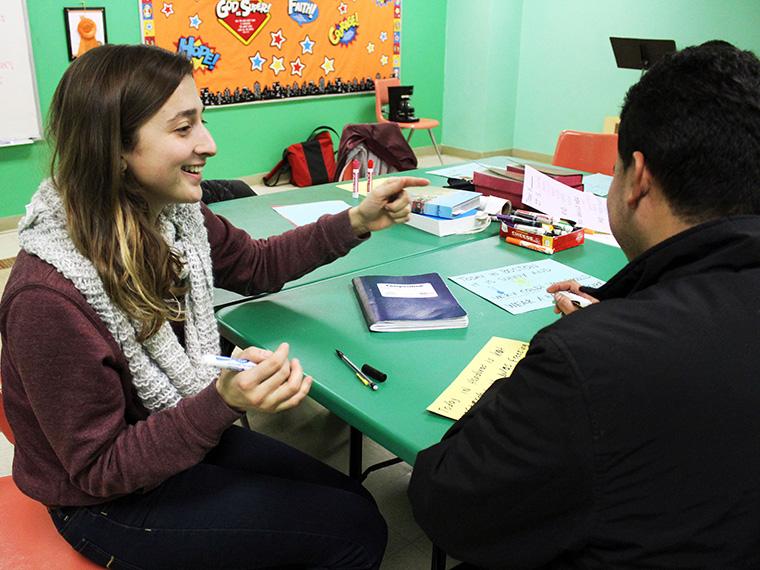 Two people sitting at a table work together on English writing skills