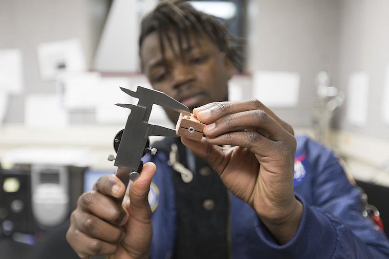 Close-up photo of Daniel Mukasa working with tools in the lab