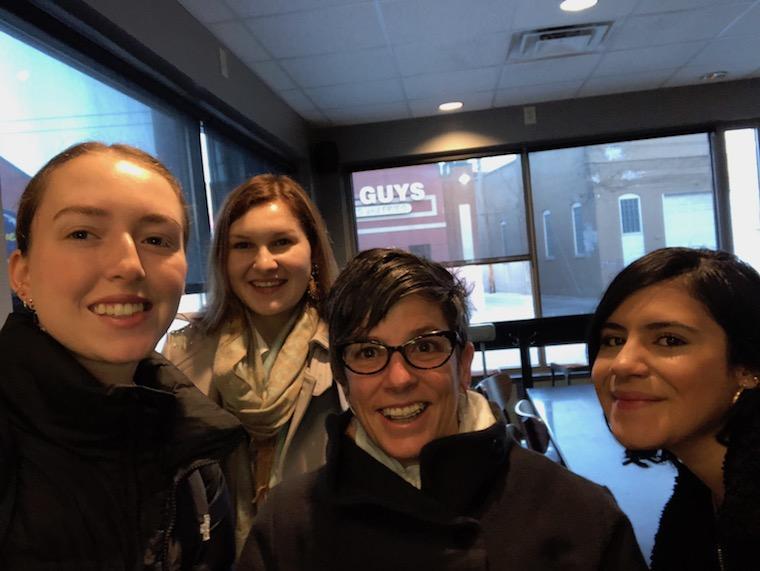  a smiling professor surrounded by three students