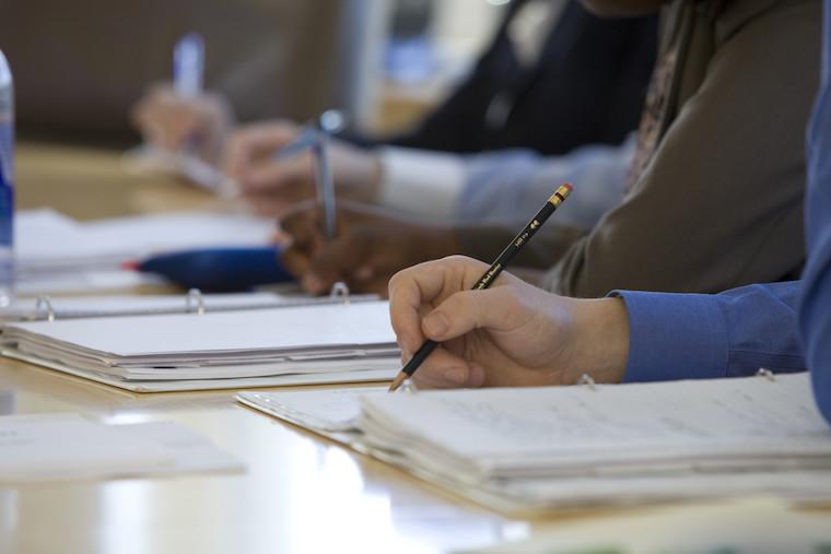 Close-up of students taking notes at desks