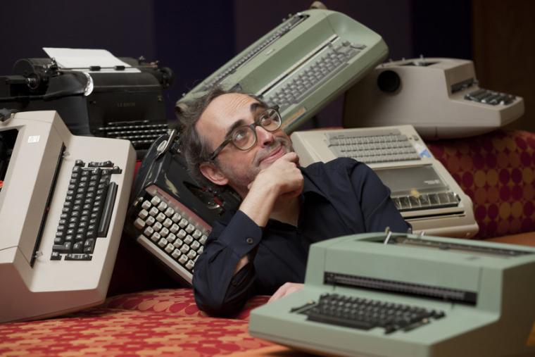 Gary Shteyngart makes a silly, introspective pose amidst typewriters 