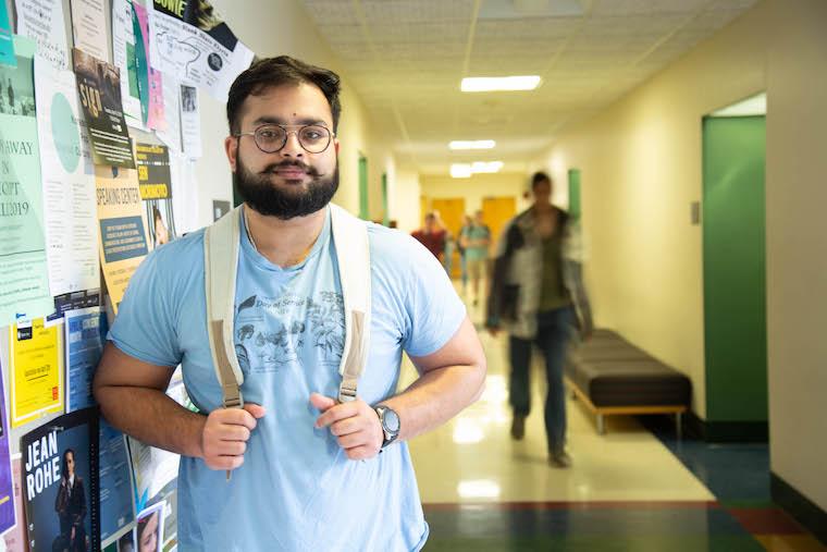 Gaurab Pokharel posing in a busy hallway in King, leaning against a bulletin board.