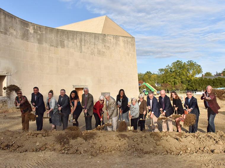 Individuals use shovels during a groundbreaking ceremony for The Eric Baker Nord Performing Arts Annex and Hall Annex.