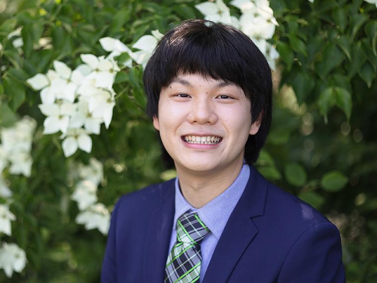 a smiling student wearing a suit coat and tie