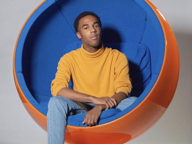 young black man sitting in a  circular "womb" chair.