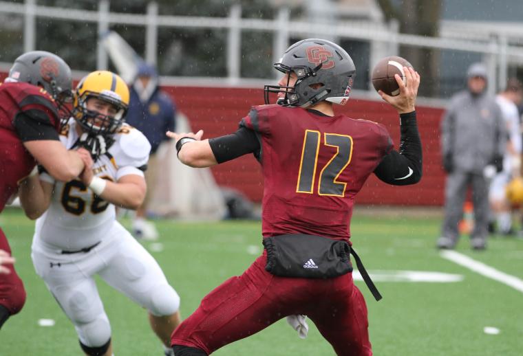 Oberlin querterback wearing number 12 cocks his arm to pass while an oncoming defender tries to evade a block..