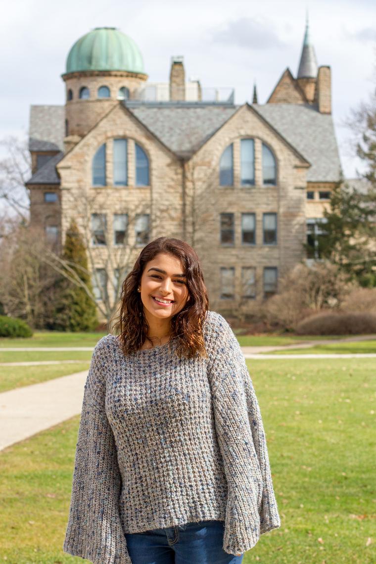 Photo of Ilana Foggle posing in front of a campus background