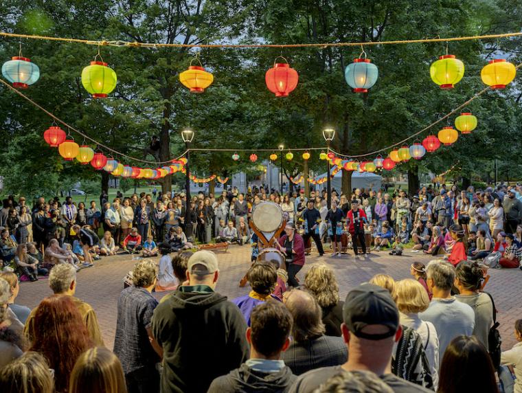 A crowd encircles Taiko drum performers beneath colorful paper lanterns.