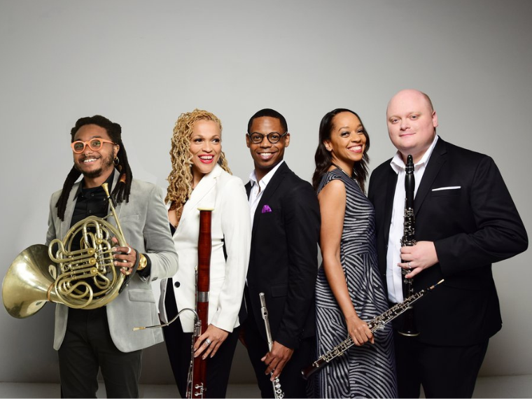 five people standing holding instruments and smiling