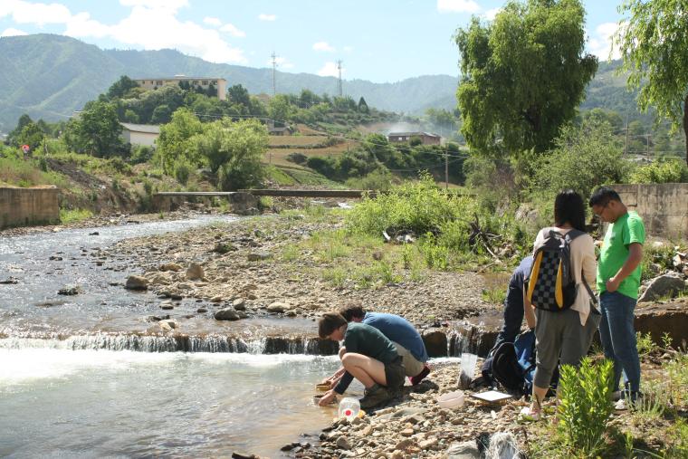 Students taking soil samples from the edge of a river