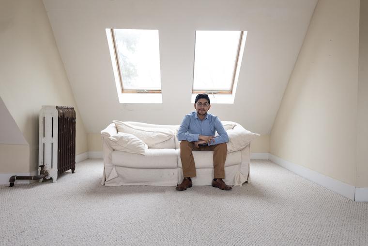 Photo of Jesus Martinez seated on a white couch in a room with skylights behind him