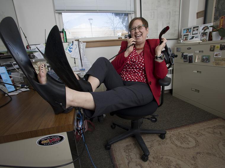 Jill Medina sits at her desk wearing scuba flippers