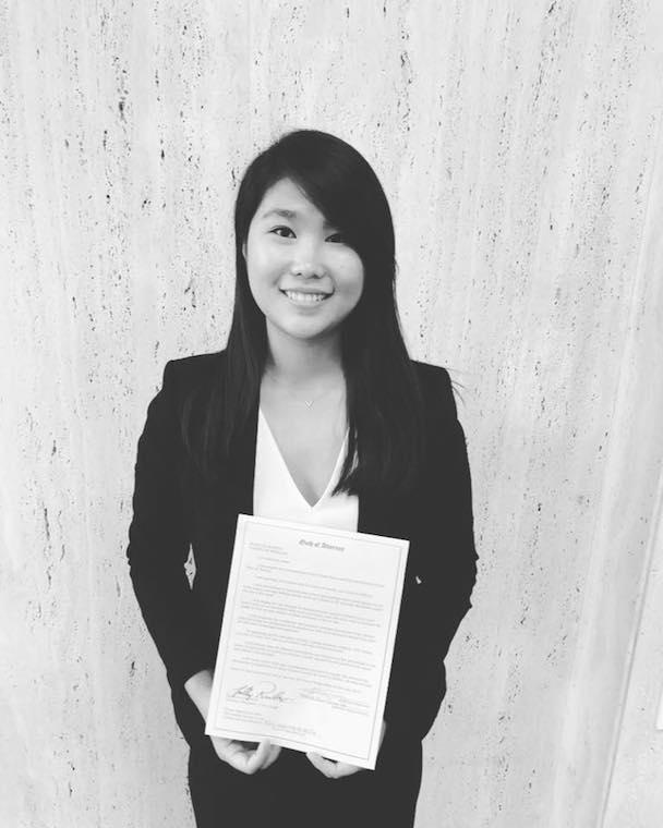 black and white image of Asian woman holding a piece of paper.