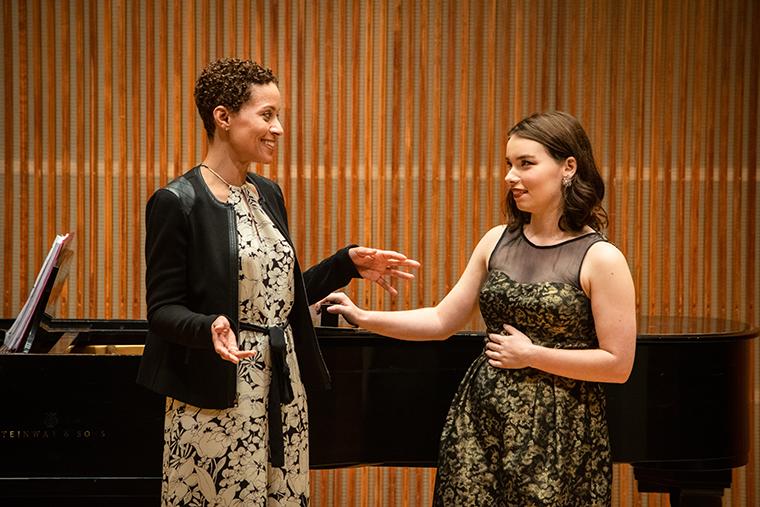Jolly teaching student standing in front of piano