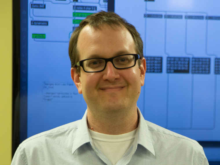 Steven Kemper portrait - man with short brown hair and glasses wearing a light blue shirt