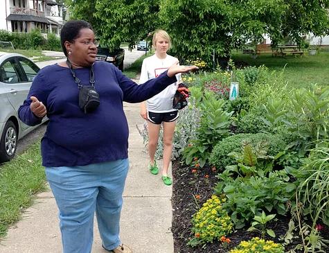 Two women tour a garden along a city sidewalk