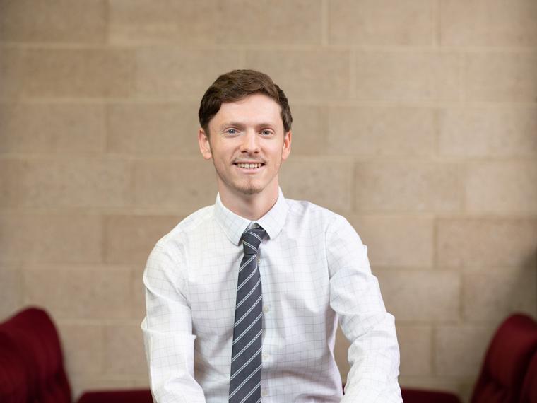 Leo Hochberg young man in white shirt, gray striped tie sitting in room.