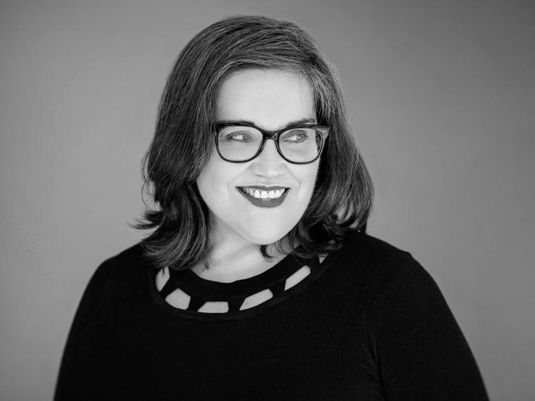 a person wearing glasses smiles and looks off camera to the right