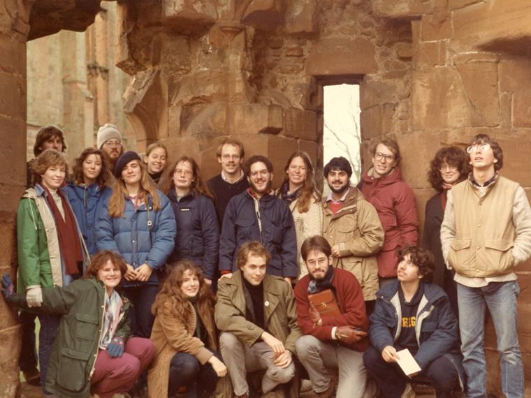 A group of students wearing jackets in front of a stone edifice.