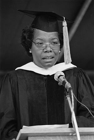 Maya Angelou at the podium in academic regalia. Black and white photo.