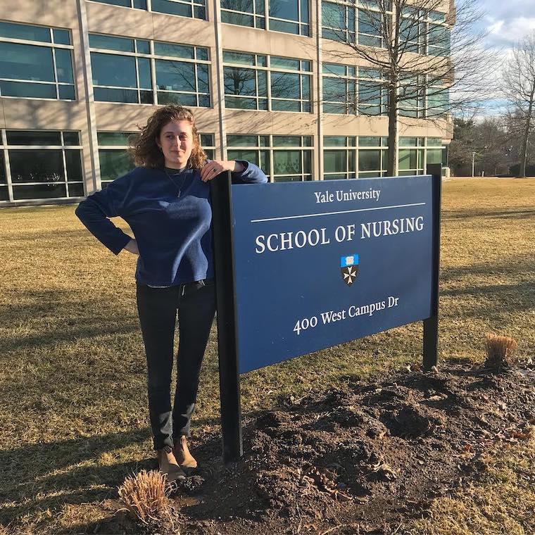 Maya Zeemont leans against the Yale School of Nursing sign