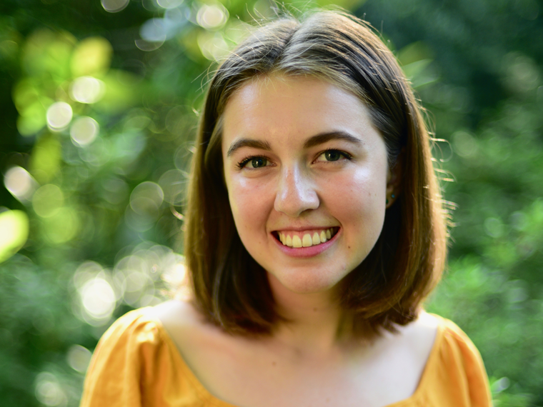 Headshot of Milena Kagel wearing yellow shirt and smiling in the sunlight.