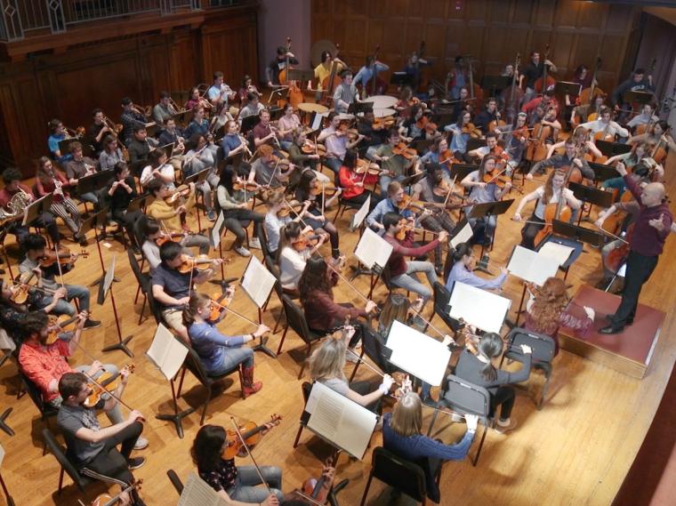 orchestra musicians rehearsing together on stage.