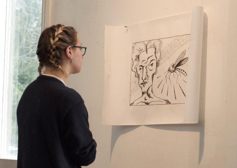 A student examines a print tacked to the wall.