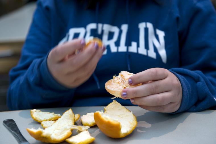 Close-up of a person peeling an orange.