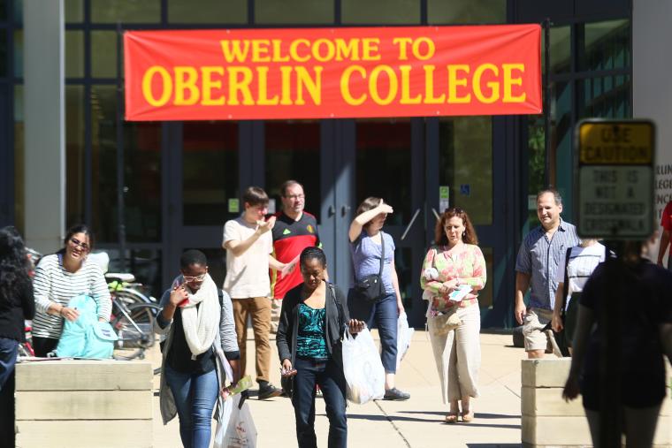 At a building entrance, people walk under a banner reading Welcome to Oberlin College.
