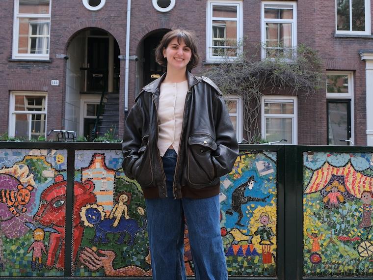 Student stands in front of colorful wall.