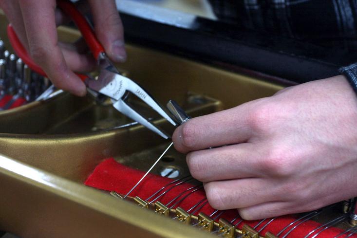 A technician works on a piano.