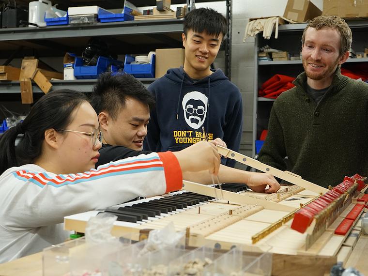 Piano technology students works on an instrument in the shop.