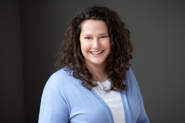 woman in light blue sweater and while top seated for photo.