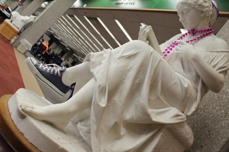 The Reading Girl statue is wearing a Converse sneaker and a bright purple necklace.