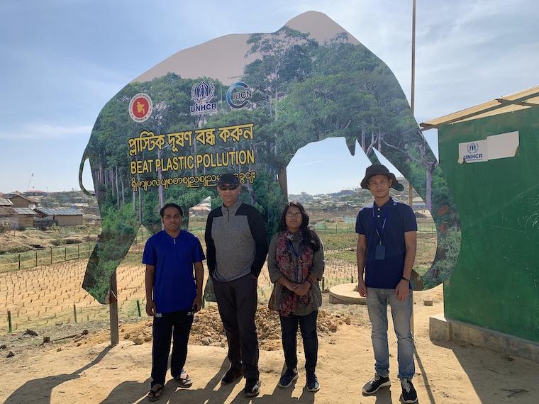 Rumi Shammin stands with three people in front of sign that reads "Beat Plastic Pollution." Photo.