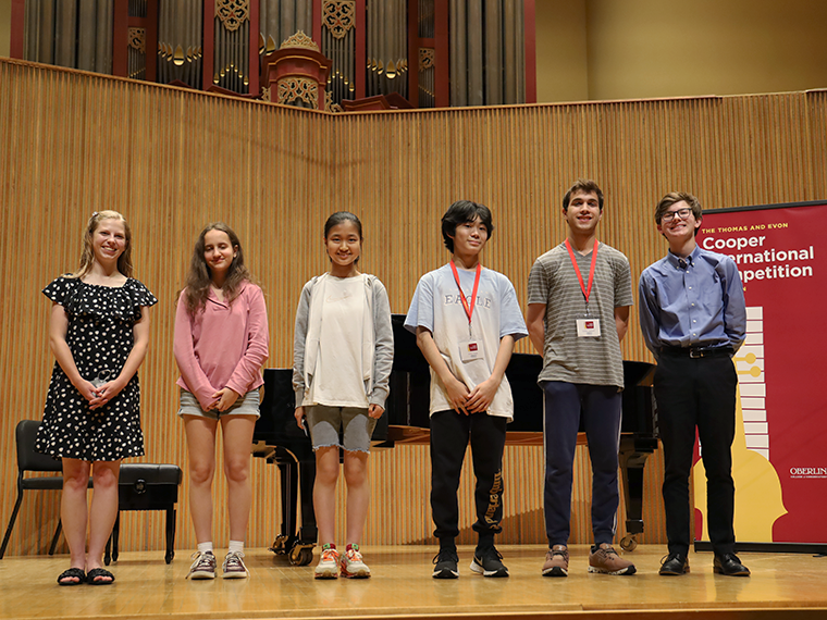 Six young musicians, three girls and three boys, stand on Warner Concert Hall Stage.