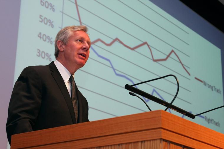 Jim Margolis at a speaking podium. A line chart is projected on the screen behind him.