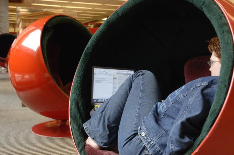 A student reads, curled up in a ball chair