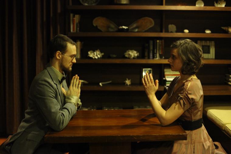 Two people sit kneeling and praying at a coffee table
