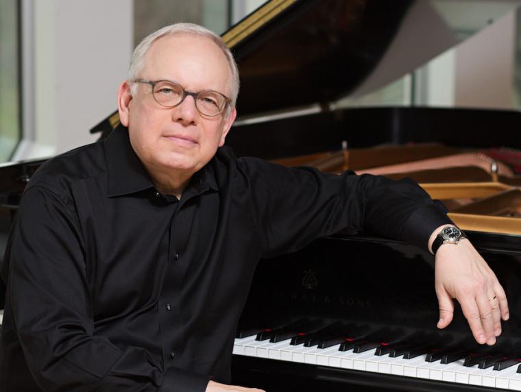 piano professor Peter Takacs seated at a piano.