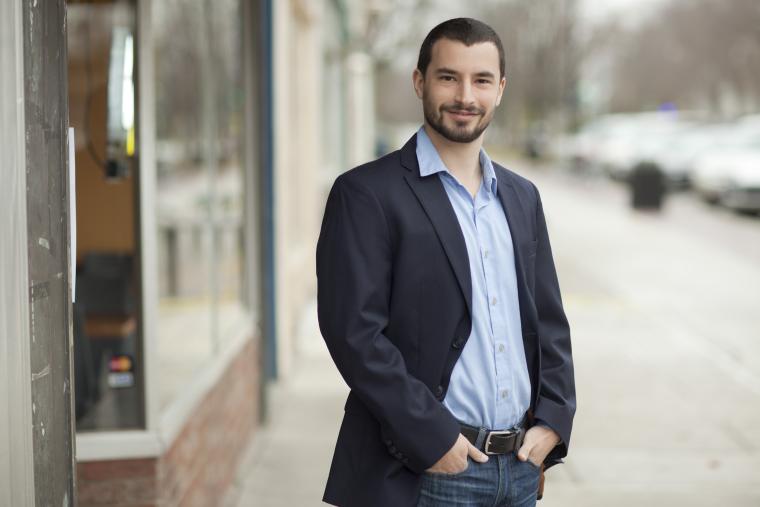 young man standing with hands in pants pockets on downtown street.