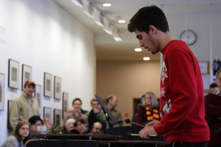 A student in a winter holiday sweater plays the marimba