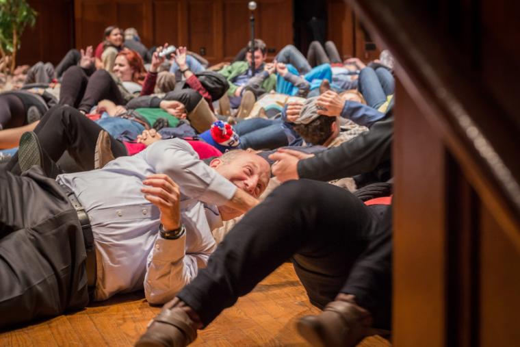 Students and President Krislov lie on the stage floor