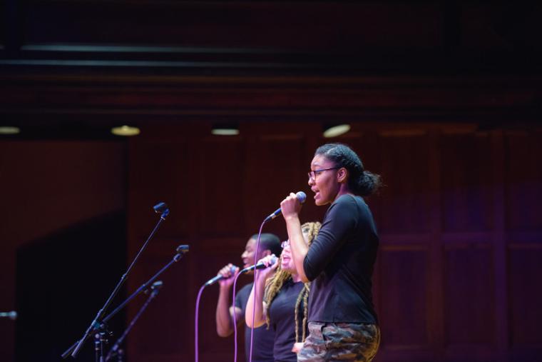 3 students on stage with microphones