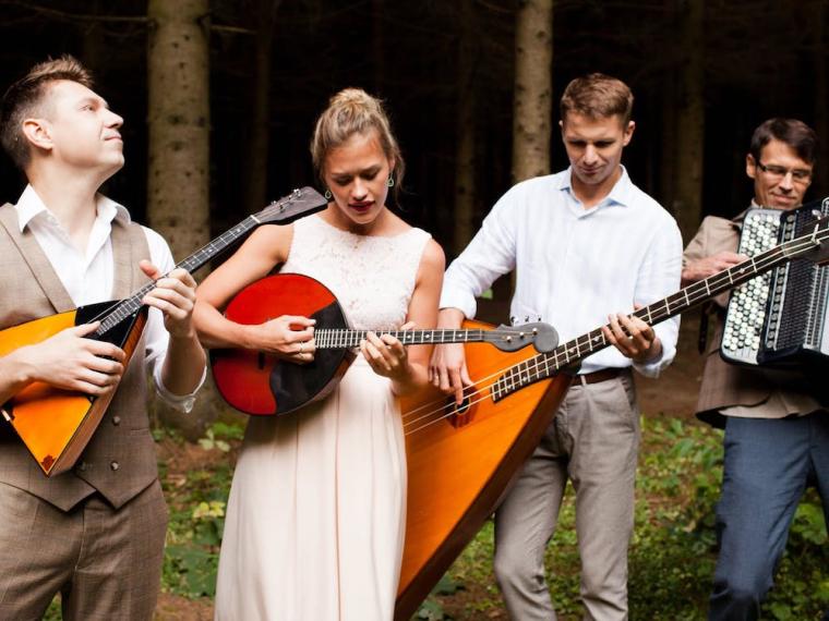 four Russian musicians playing their instruments in a forest