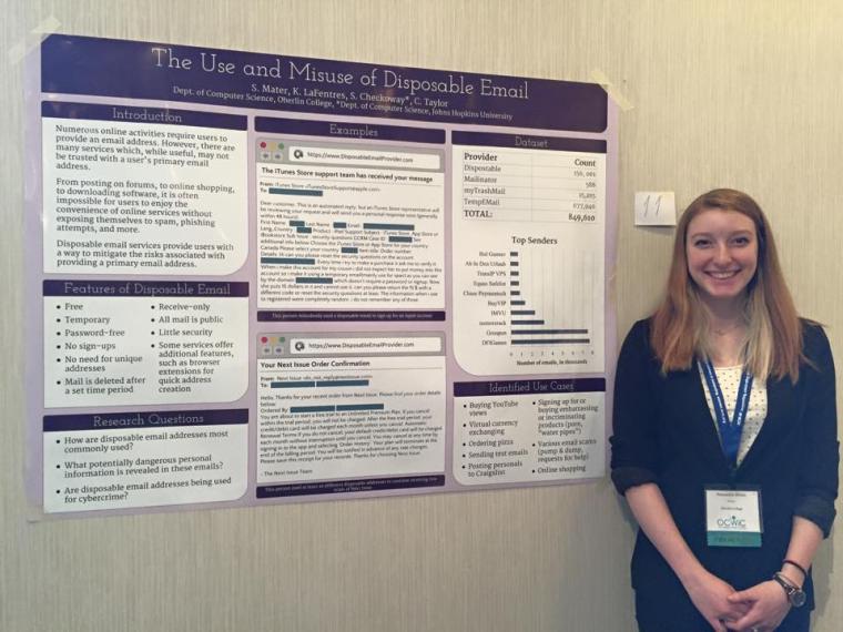 A student poses for the photo next to a research poster