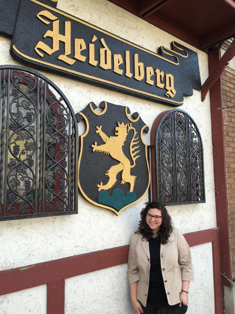 Sarah stands outside an establishment. The sign says 'Heidelberg'.