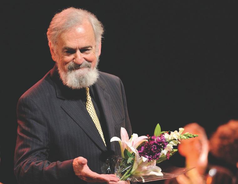 man holding flowers smiling at audience