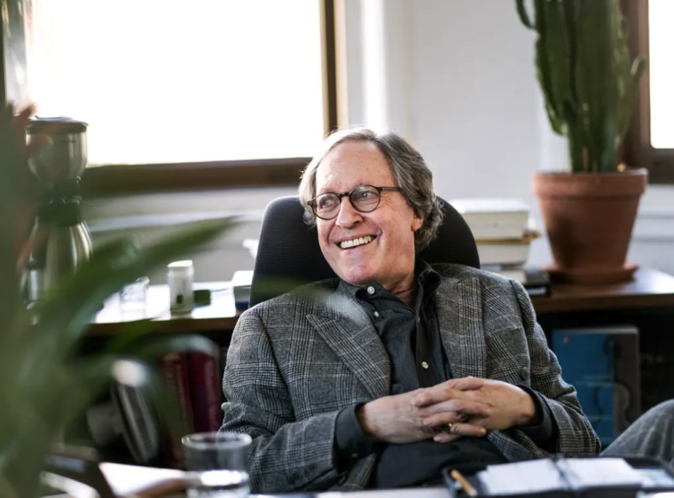 photo of smiling man seated behind a desk